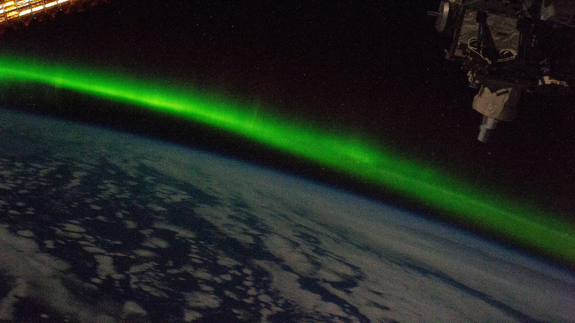 Green aurora arcing over the curve of Earth, seen from the International Space Station.