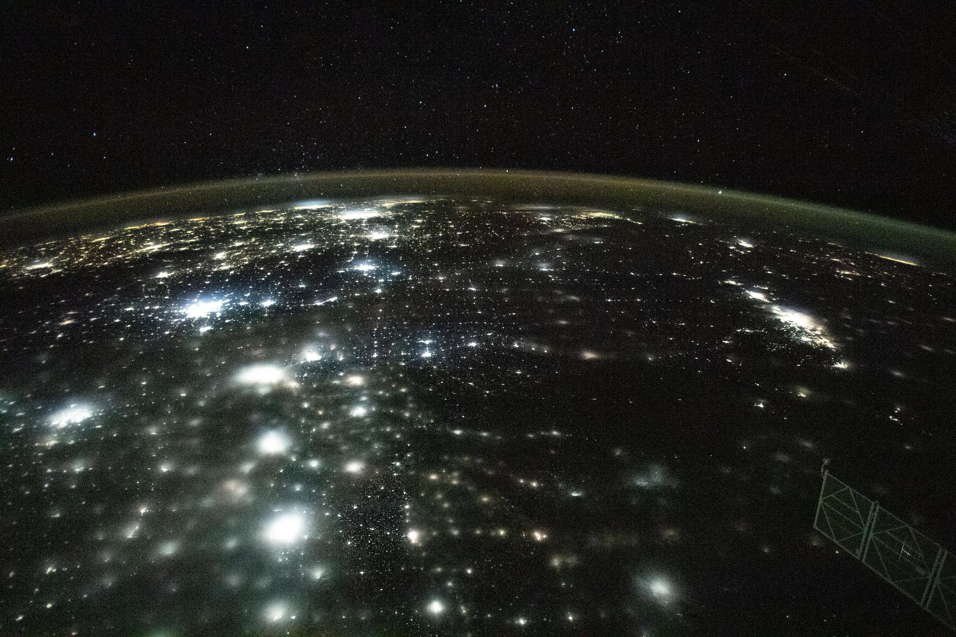 Earth at night from orbit, city lights tracing dense terrestrial networks.